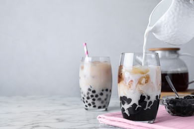 Photo of Preparing bubble milk tea with tapioca balls on white marble table. Space for text