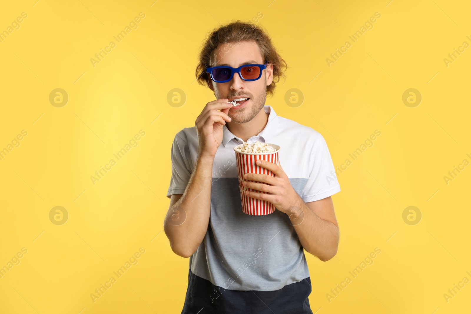 Photo of Man with 3D glasses and popcorn during cinema show on color background