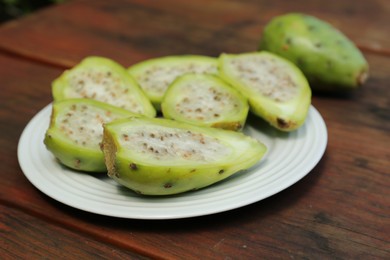 Tasty prickly pear fruits on wooden table, closeup