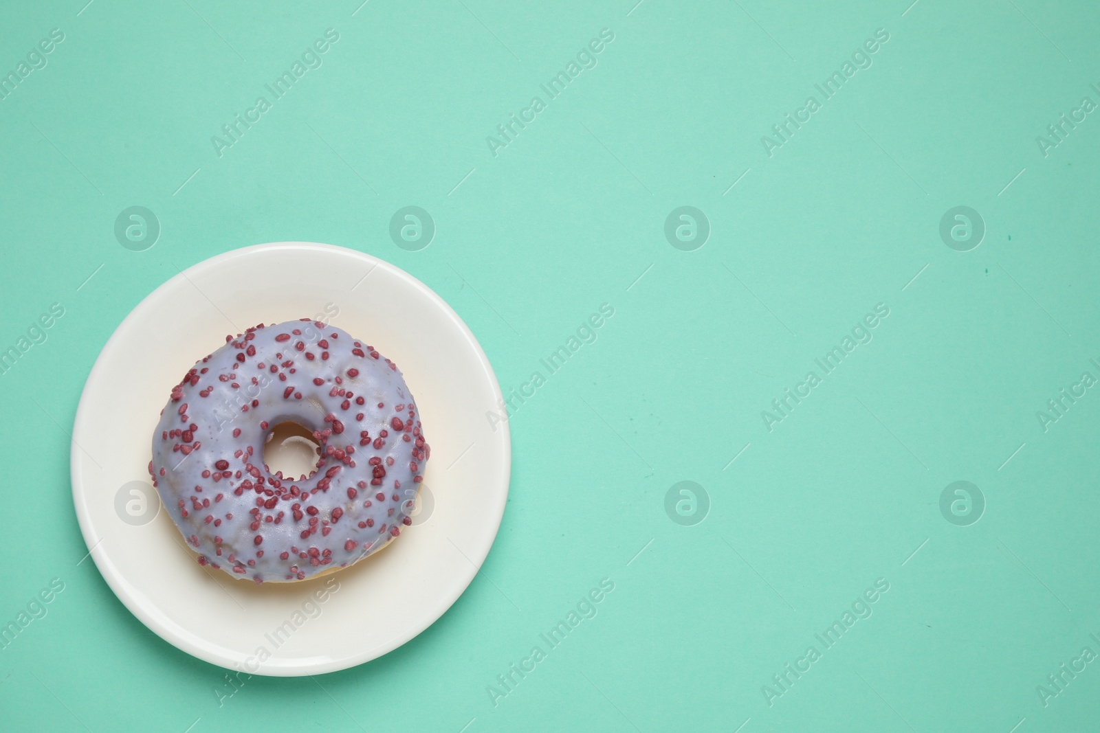 Photo of Delicious glazed donut on turquoise background, top view. Space for text