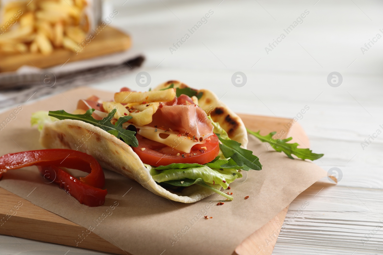 Photo of Delicious pita wrap with jamon, vegetables and greens on wooden table