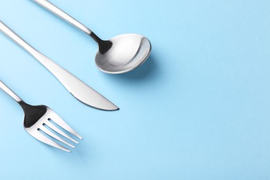 Photo of Stylish cutlery set on light blue table, closeup. Space for text