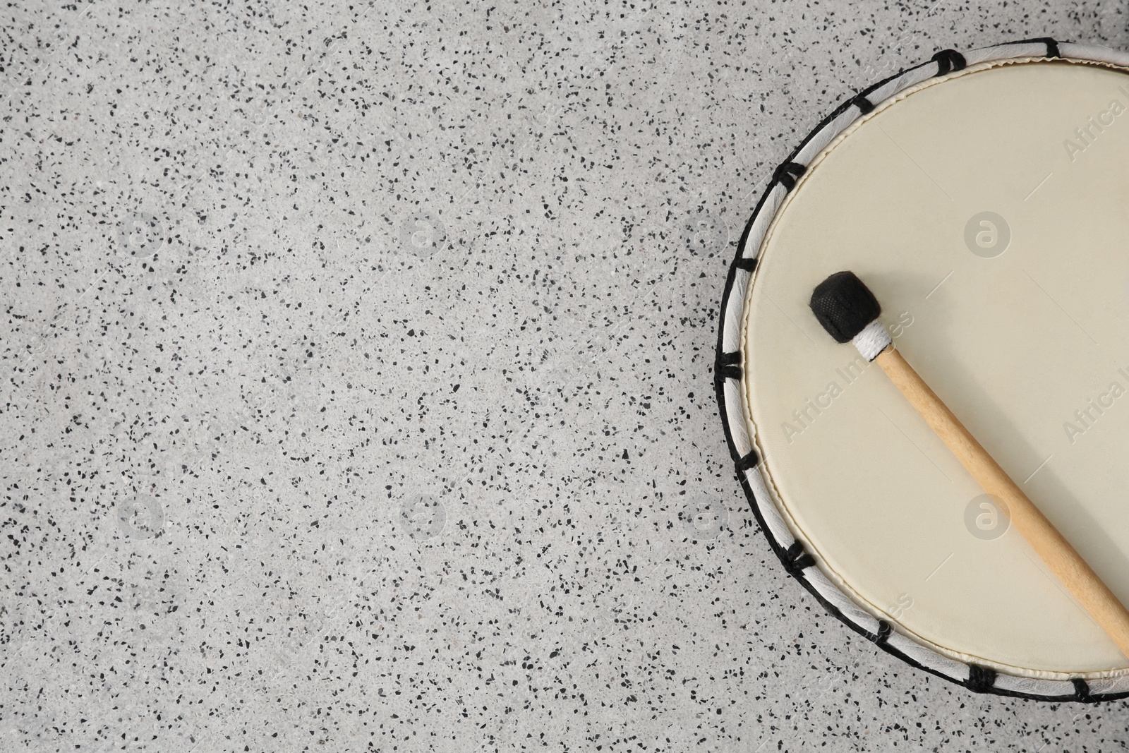 Photo of Drum and drumstick on grey table, top view with space for text. Percussion musical instrument