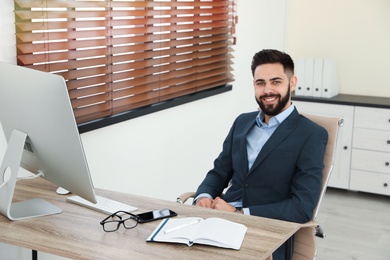 Photo of Handsome businessman working at table in office