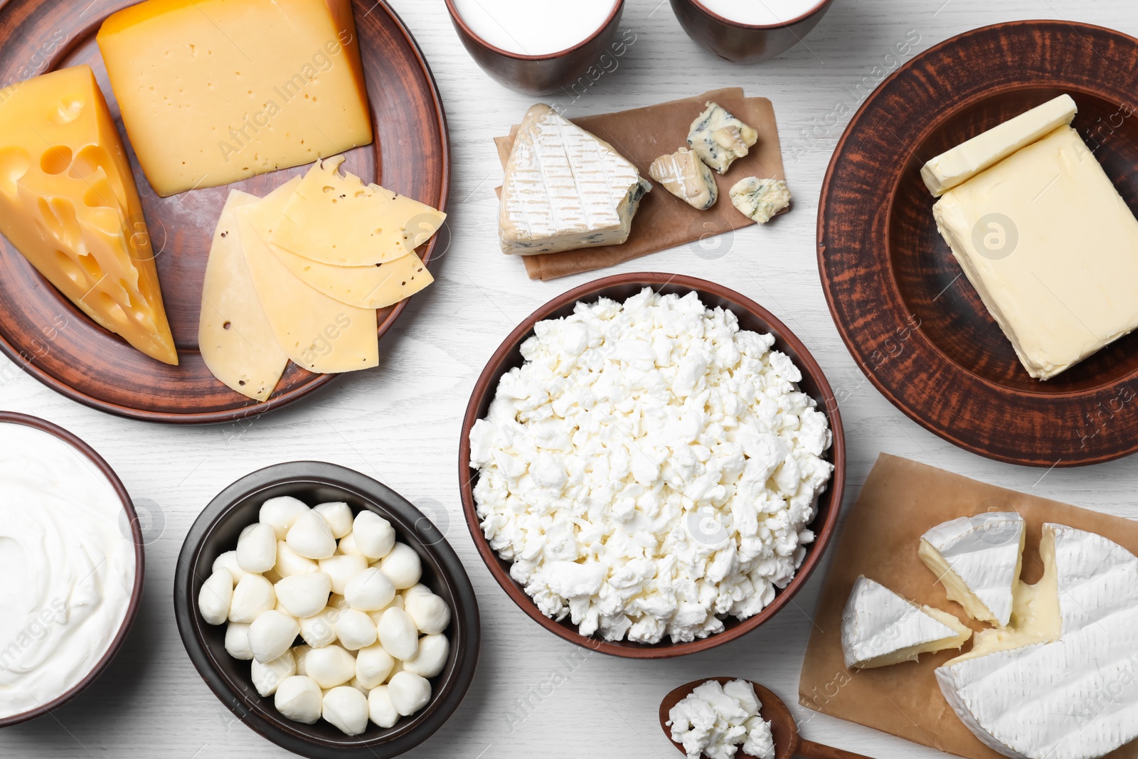 Photo of Clay dishware with fresh dairy products on white wooden table, flat lay