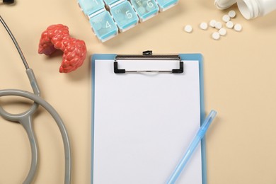 Endocrinology. Flat lay composition with clipboard and model of thyroid gland on beige background