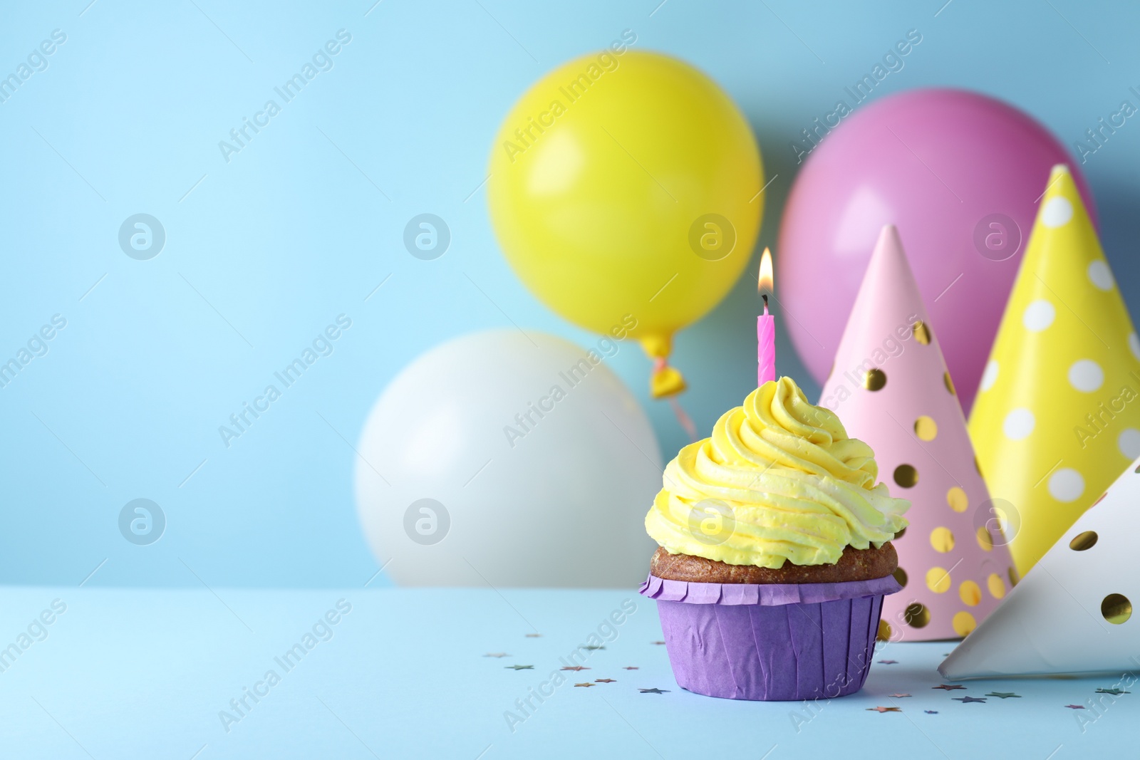 Photo of Delicious birthday cupcake with candle on light blue background, space for text