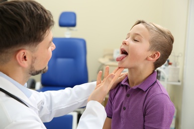 Photo of Male otolaryngologist examining little child in hospital
