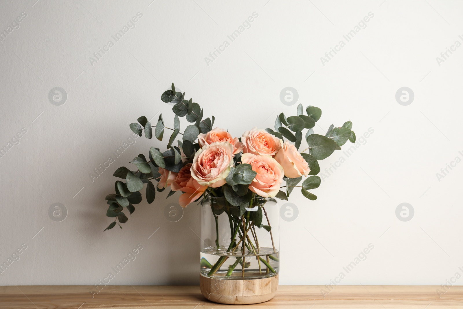 Photo of Bouquet with beautiful flowers in glass vase on wooden table against white background
