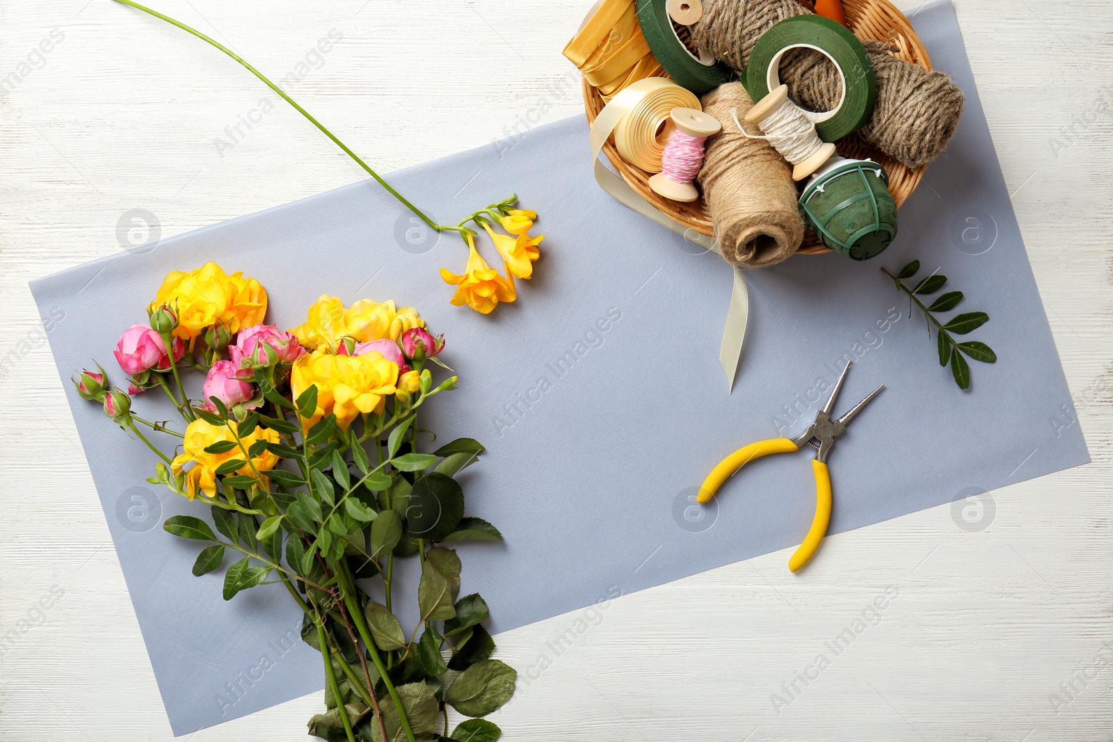 Photo of Florist supplies with flowers on wooden background, top view