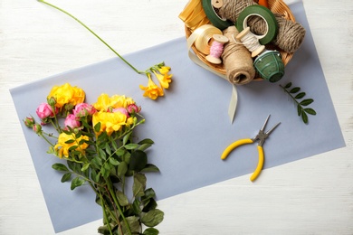 Florist supplies with flowers on wooden background, top view