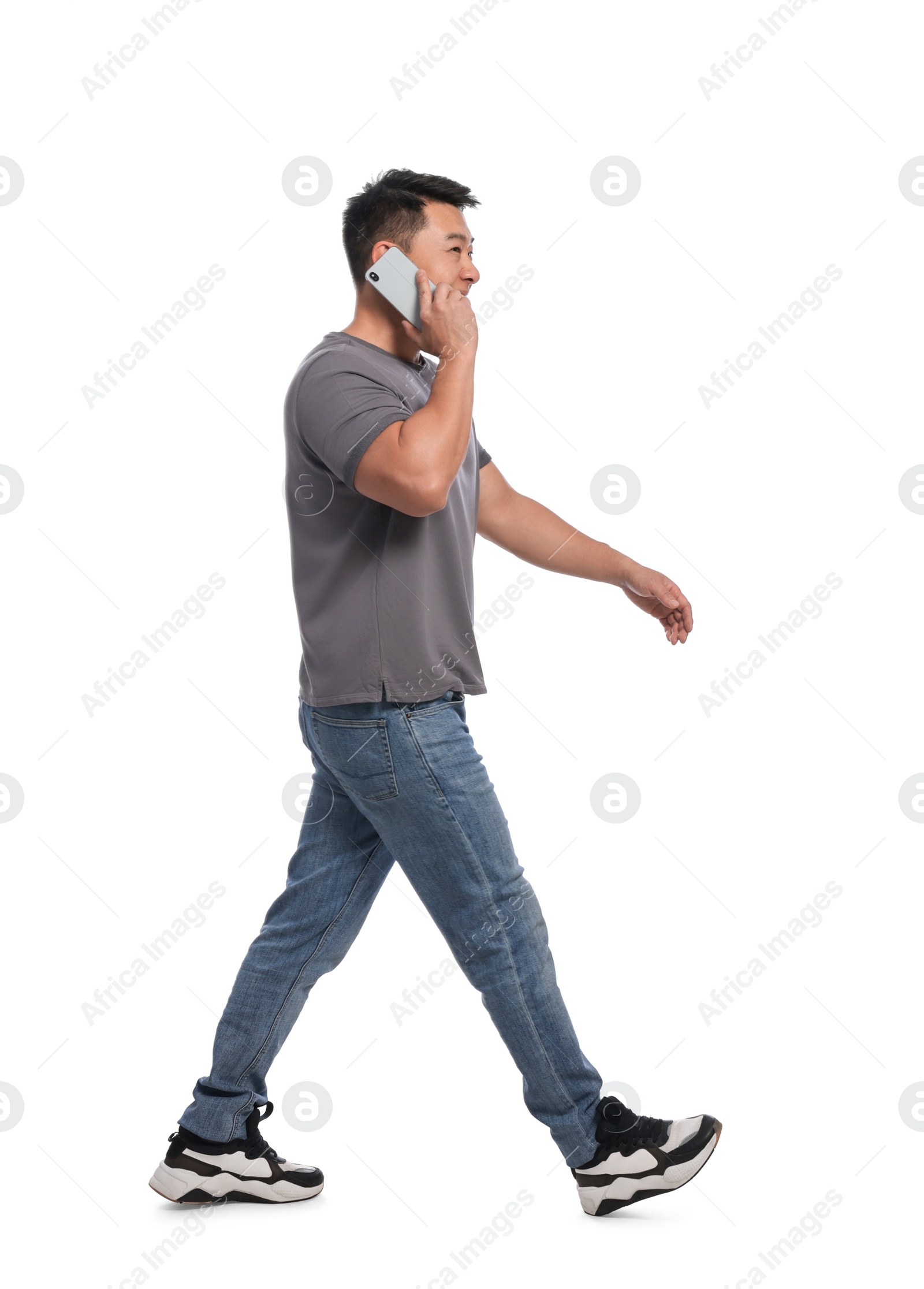 Photo of Man talking on smartphone while walking against white background