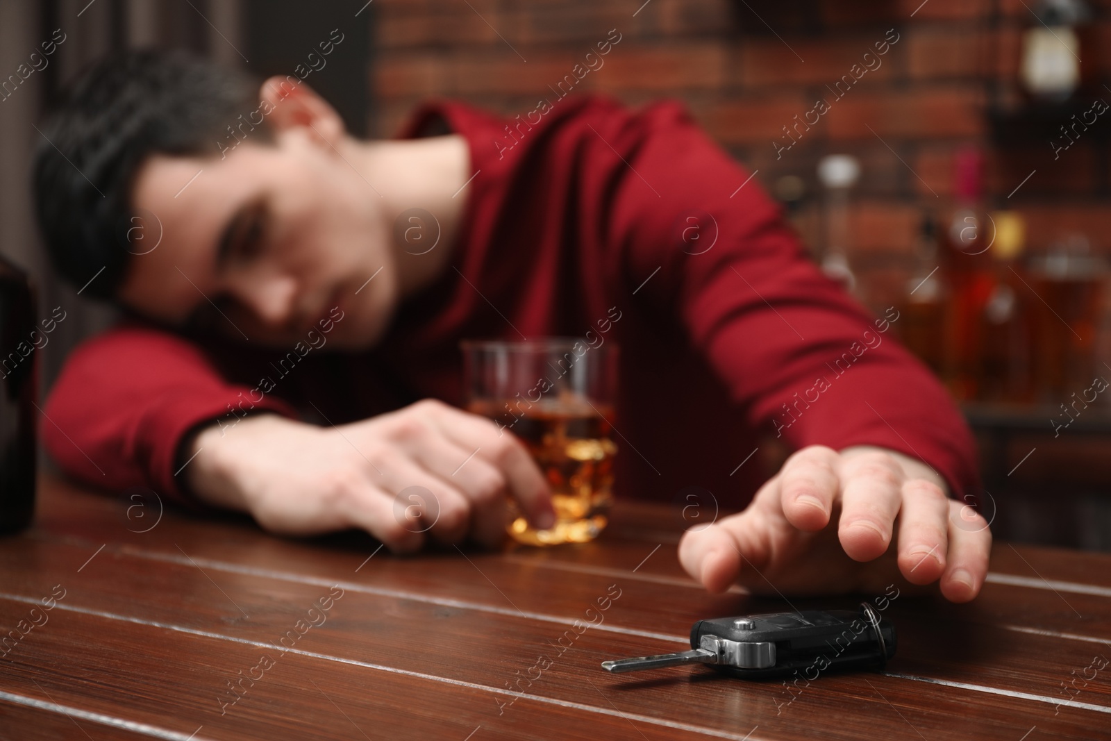 Photo of Drunk man reaching for car keys at table, closeup. Don't drink and drive concept