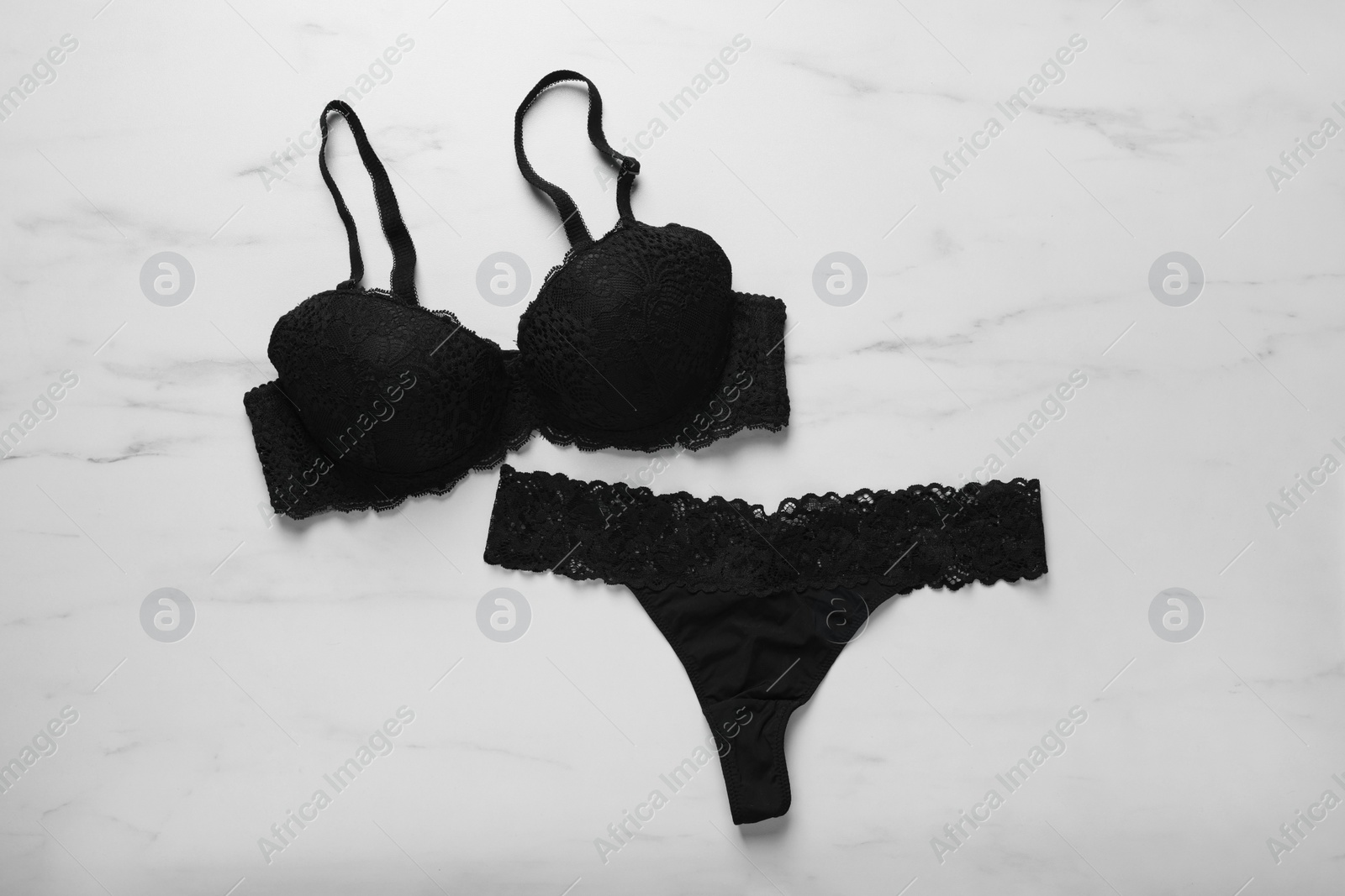 Photo of Elegant black women's underwear on white marble background, flat lay