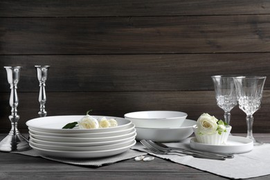 Photo of Set of clean dishware, cutlery and beautiful flowers on grey wooden table