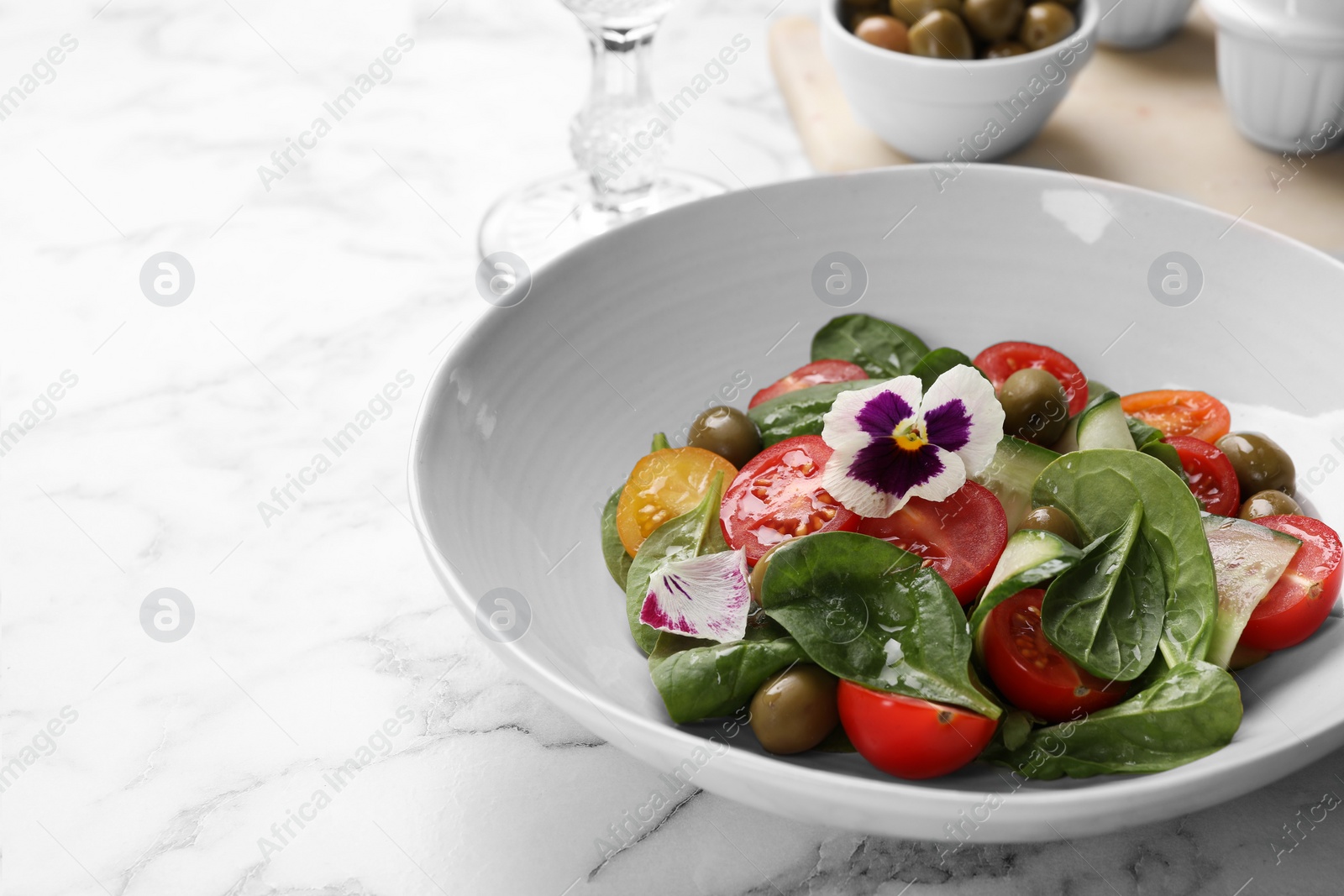 Photo of Delicious salad with vegetables and olives on white marble table