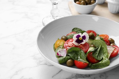 Photo of Delicious salad with vegetables and olives on white marble table