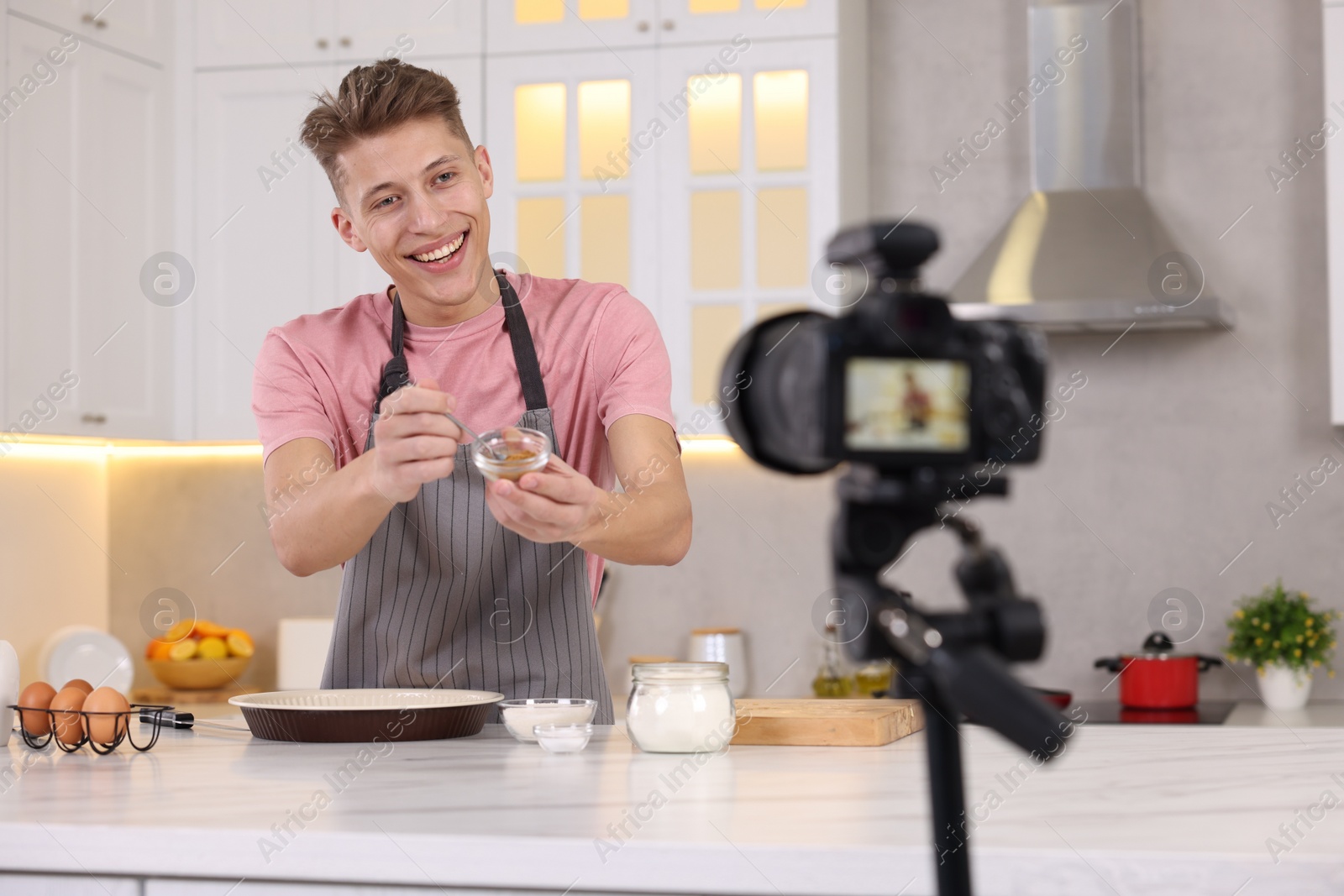 Photo of Smiling food blogger cooking while recording video in kitchen