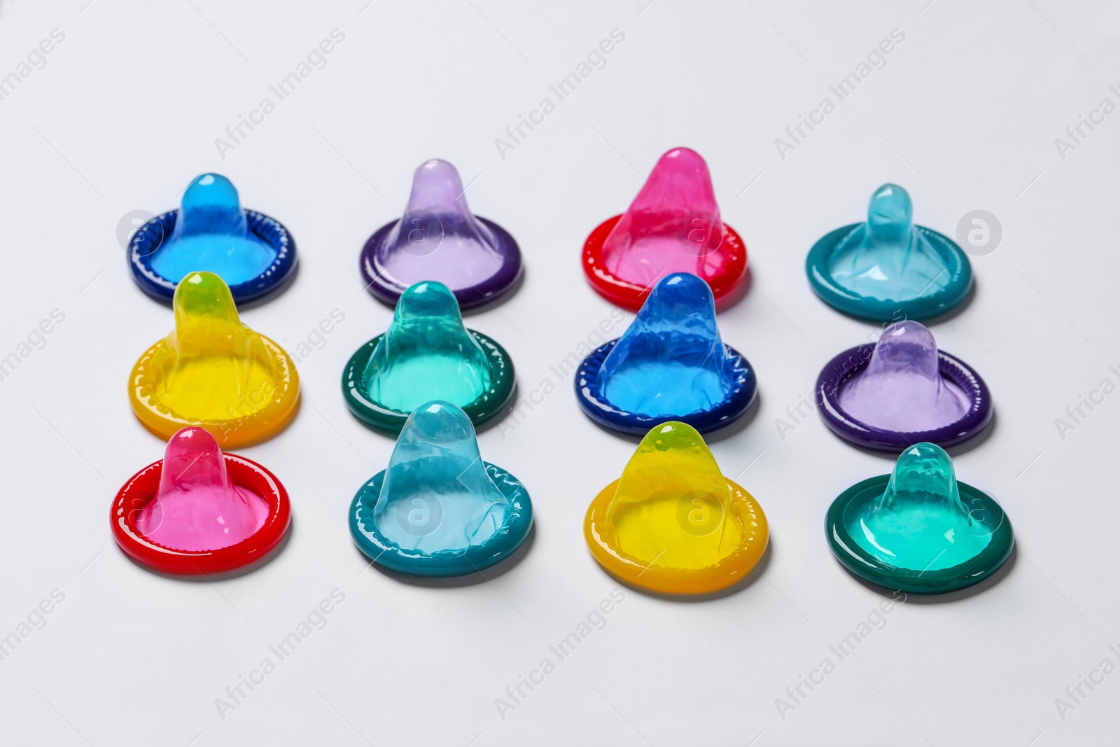 Photo of Colorful condoms on white background, closeup. Safe sex