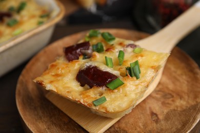 Photo of Spatula with piece of tasty sausage casserole on table, closeup