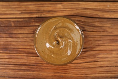 Delicious nut butter in bowl on wooden table, top view