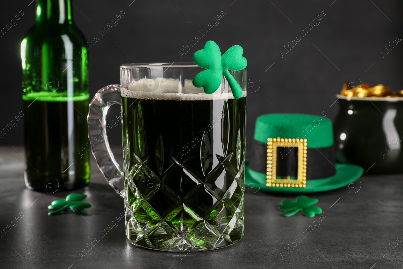 Photo of St. Patrick's day celebration. Green beer, leprechaun hat, pot of gold and decorative clover leaves on grey table