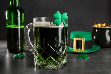 Photo of St. Patrick's day celebration. Green beer, leprechaun hat, pot of gold and decorative clover leaves on grey table