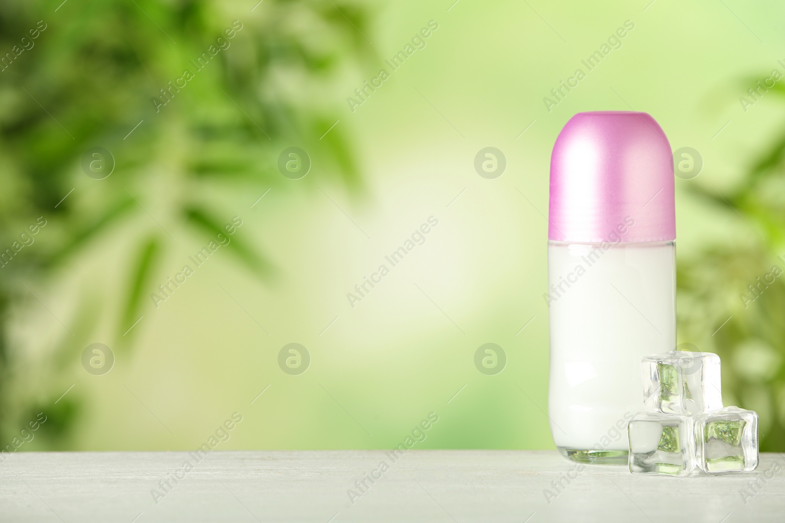 Photo of Deodorant container and ice cubes on white wooden table against blurred background. Space for text