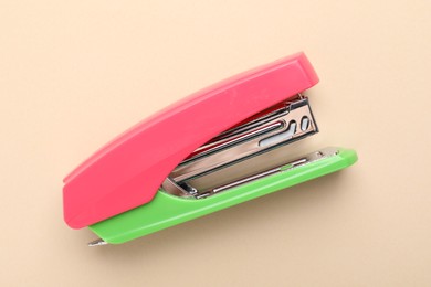Photo of One bright stapler on beige background, top view