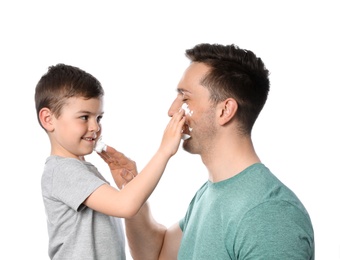 Photo of Dad and his little son applying shaving foam against white background