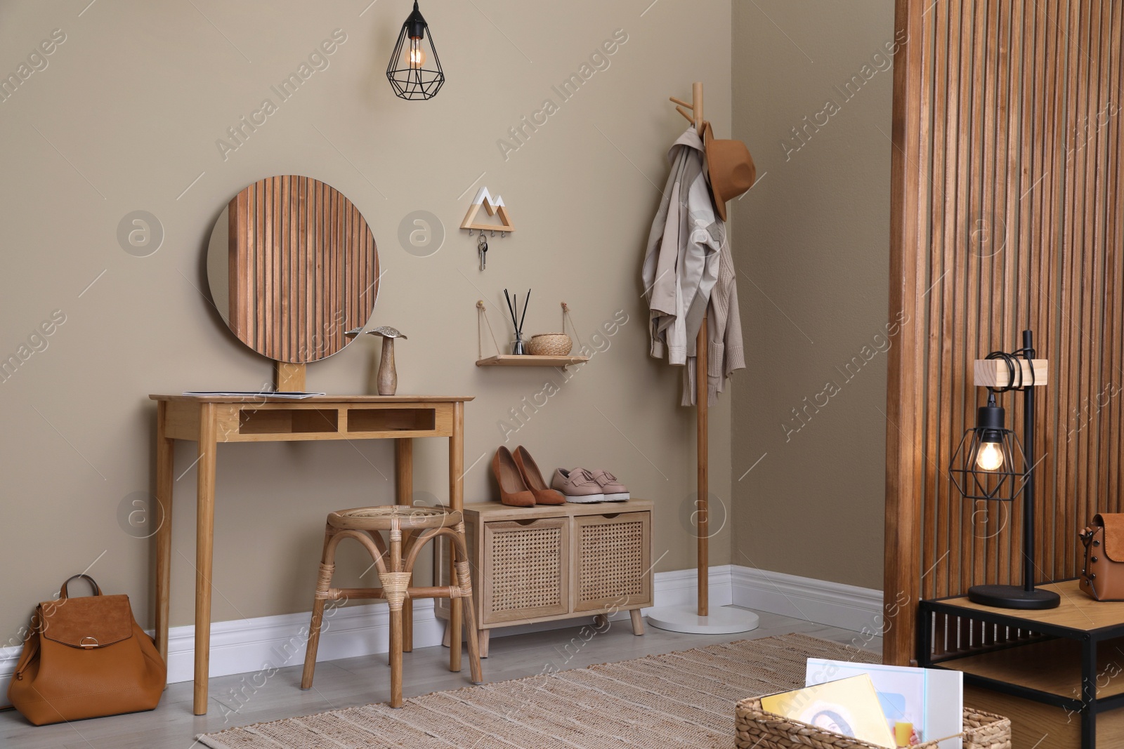 Photo of Modern hallway interior with stylish furniture, round mirror and wooden hanger for keys on beige wall