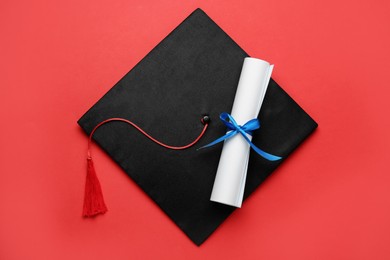 Photo of Graduation hat and diploma on red background, top view