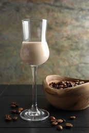 Coffee cream liqueur in glass and beans on black wooden table