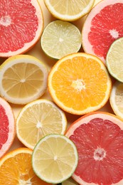 Different cut citrus fruits on beige table, flat lay