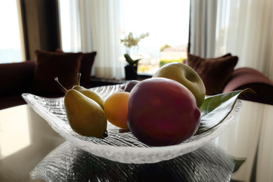 Photo of Juicy ripe fruits in vase on wooden table