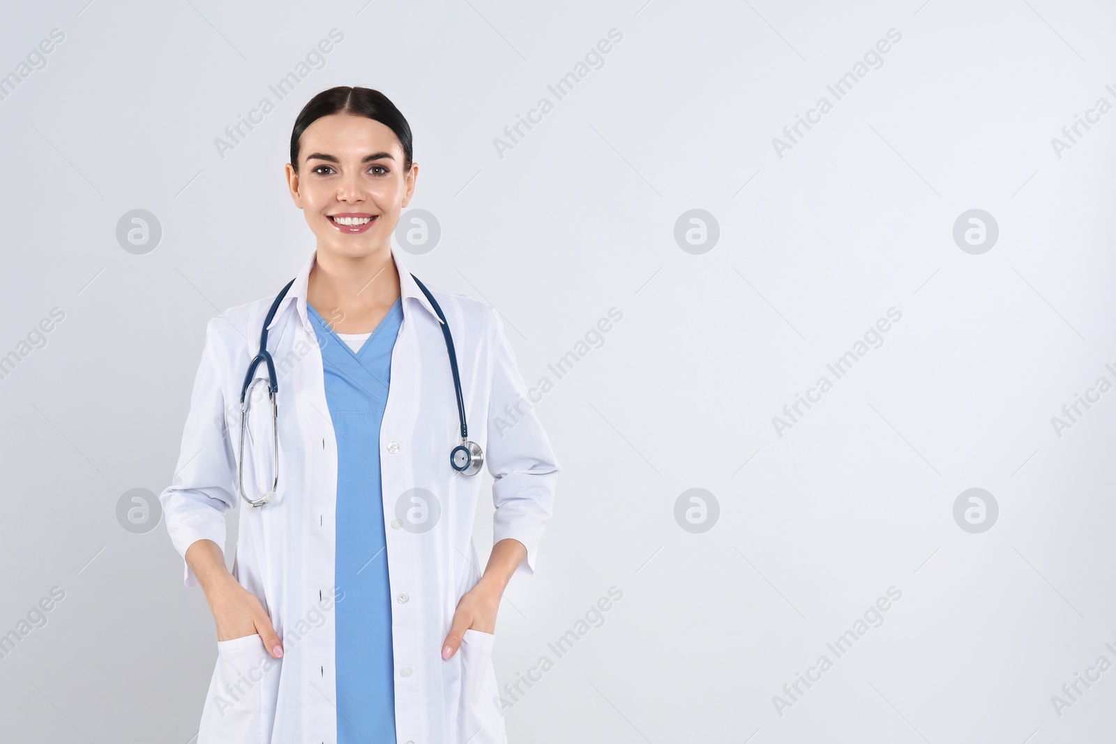Photo of Portrait of young doctor with stethoscope on white background
