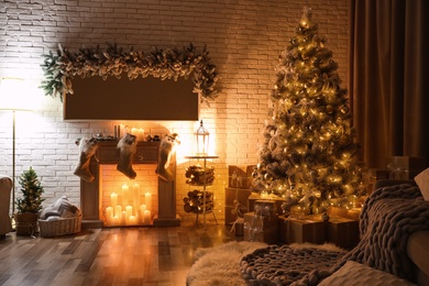 Photo of Stylish interior with beautiful Christmas tree and artificial fireplace at night