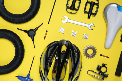 Photo of Set of different bicycle tools and parts on yellow background, flat lay