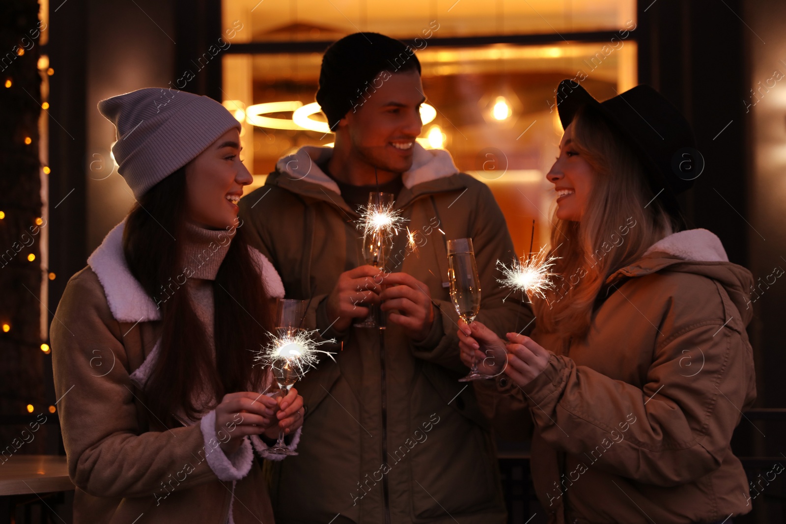 Photo of Group of happy friends with sparklers and champagne at winter fair