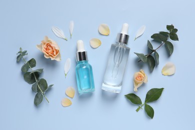 Flat lay composition with cosmetic serums on light blue background