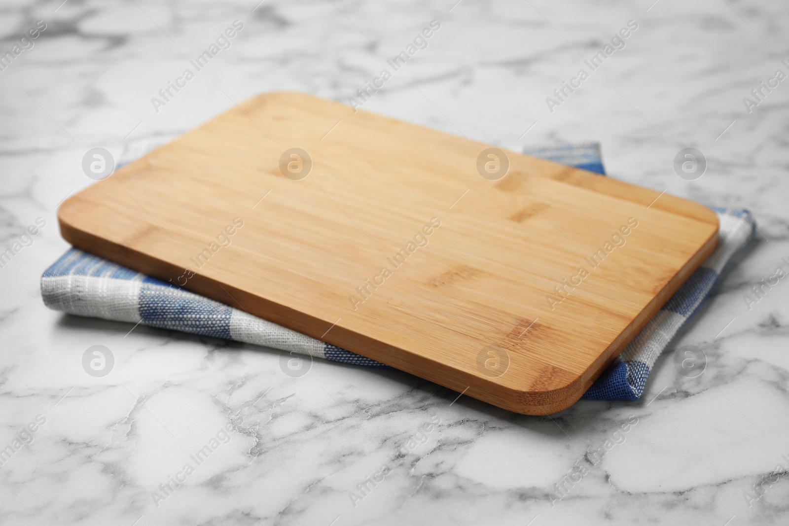 Photo of Wooden board and kitchen towel on marble table