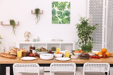 Healthy vegetarian food, glasses of juice, cutlery and plates on wooden table indoors