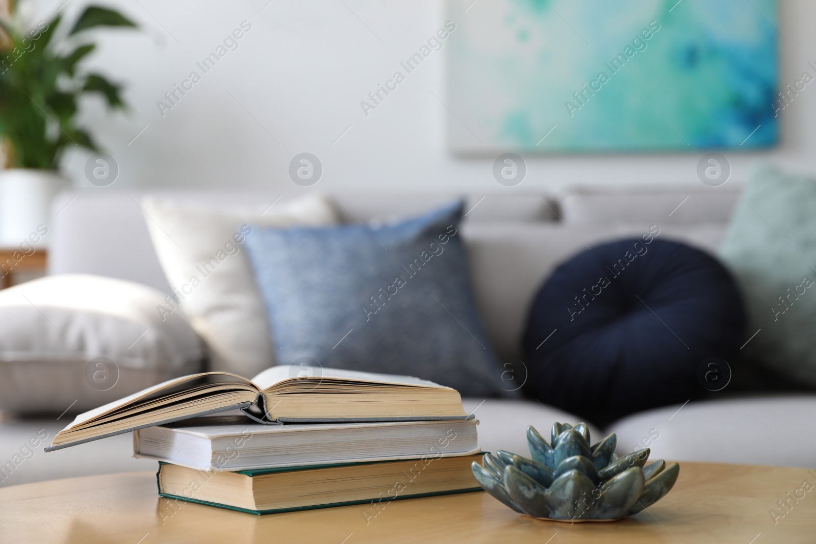 Photo of Table with books near sofa in living room. Interior design