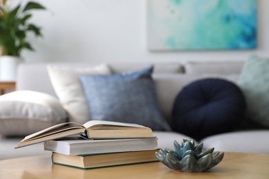 Photo of Table with books near sofa in living room. Interior design