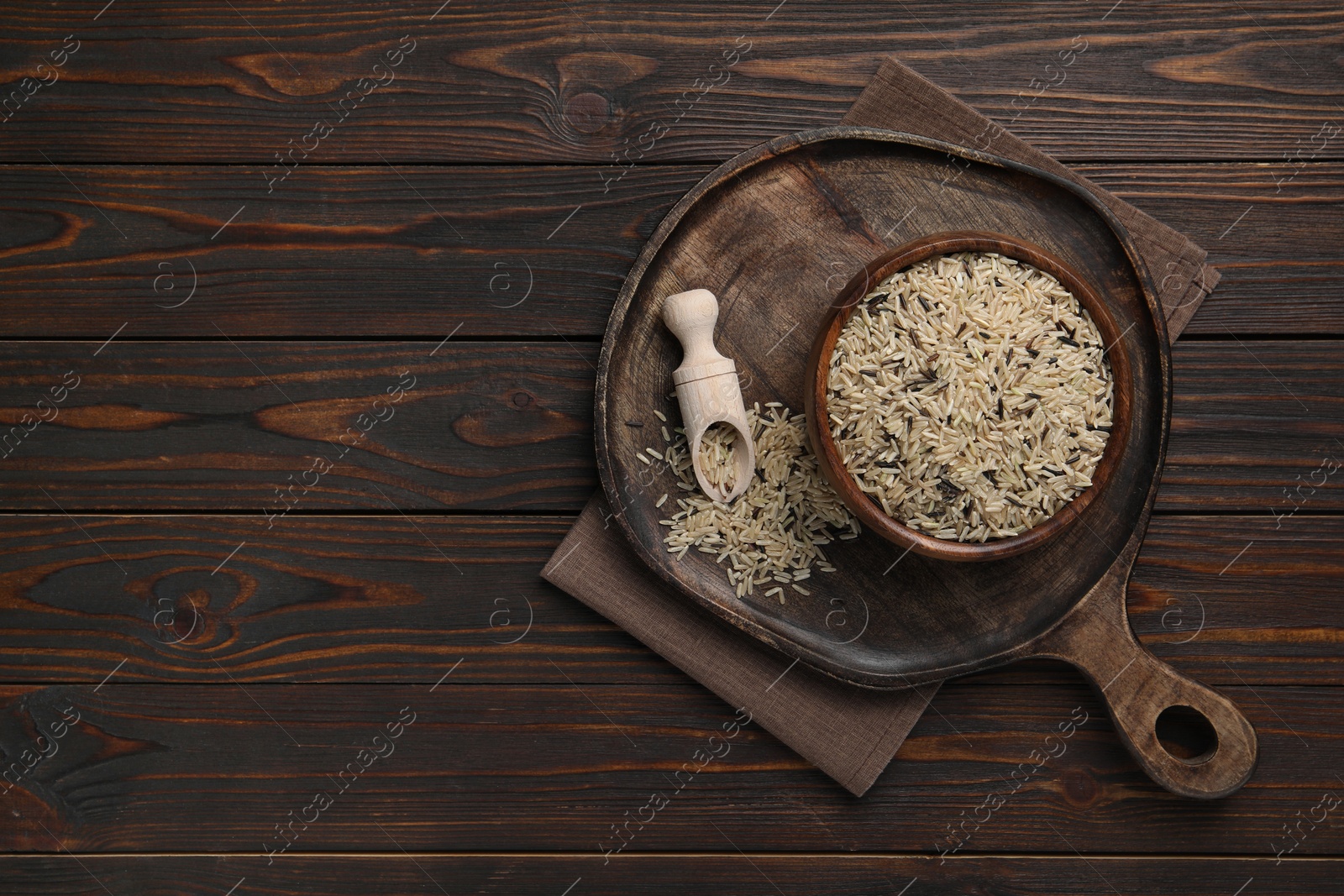 Photo of Raw unpolished rice on wooden table, top view. Space for text