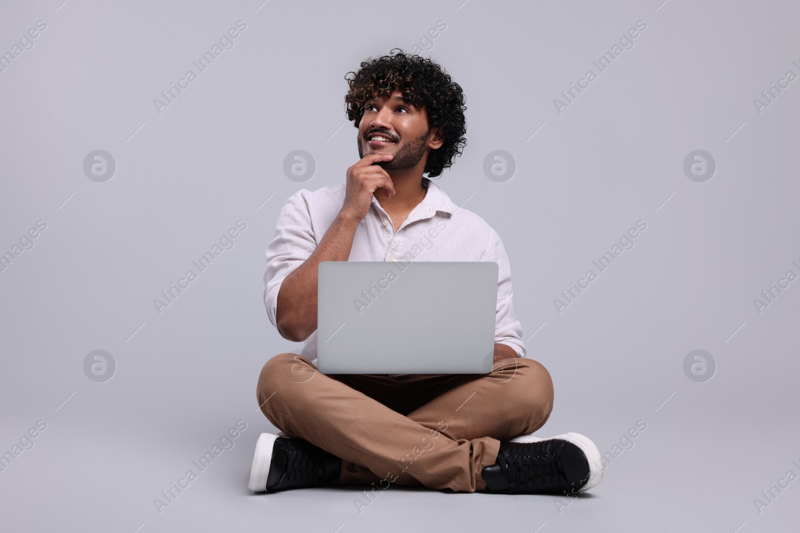 Photo of Smiling man with laptop on light grey background, space for text