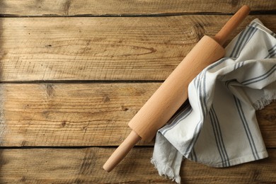 Photo of Rolling pin and kitchen towel on wooden table, top view. Space for text