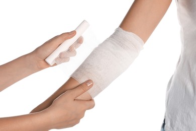 Doctor applying bandage onto patient's arm on white background, closeup