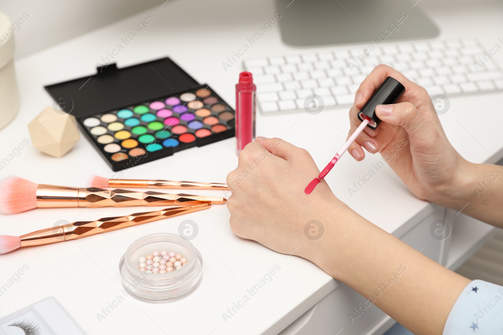 Photo of Beauty blogger doing lipgloss swatch at table, closeup