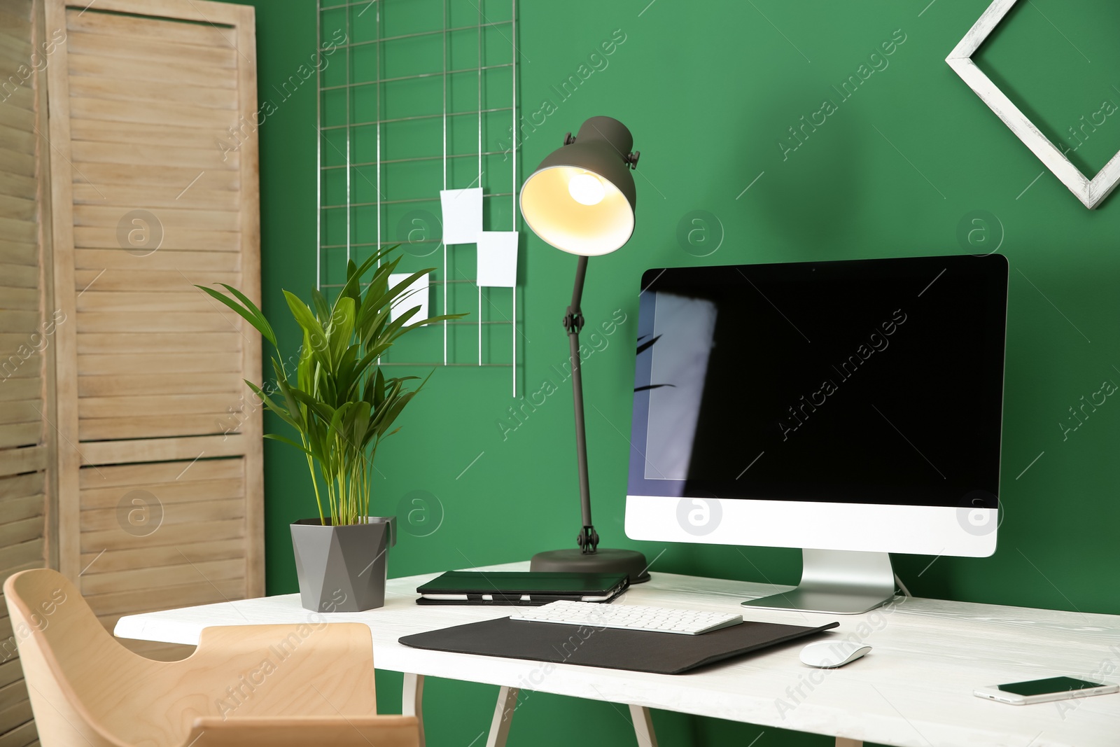 Photo of Stylish workplace with modern computer near color wall. Space for text